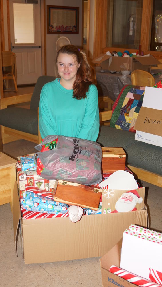 Young girl sitting in front of box of christmas presents