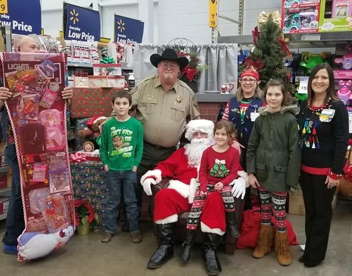 Sheriff with Santa giving a family a gift