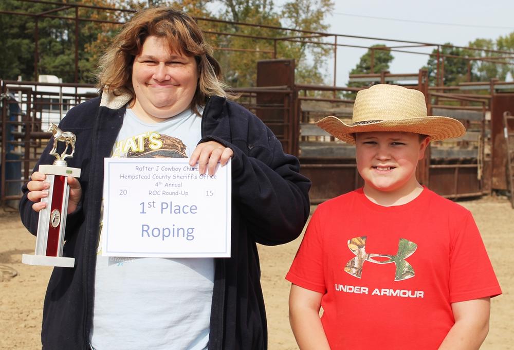 The Roping winner holding trophy and certificate, with a young person standing next to them