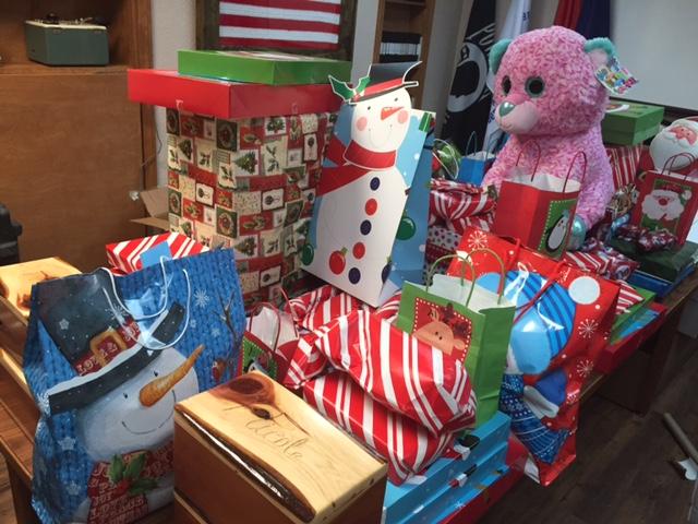 Christmas presents stacked on a table with a large stuffed pink bear