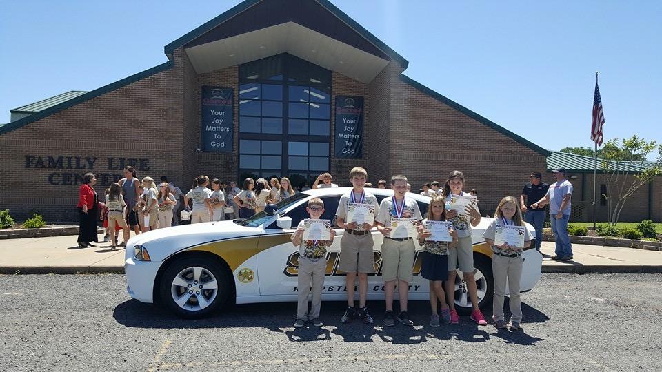 Students in front of a sheriff vehicle