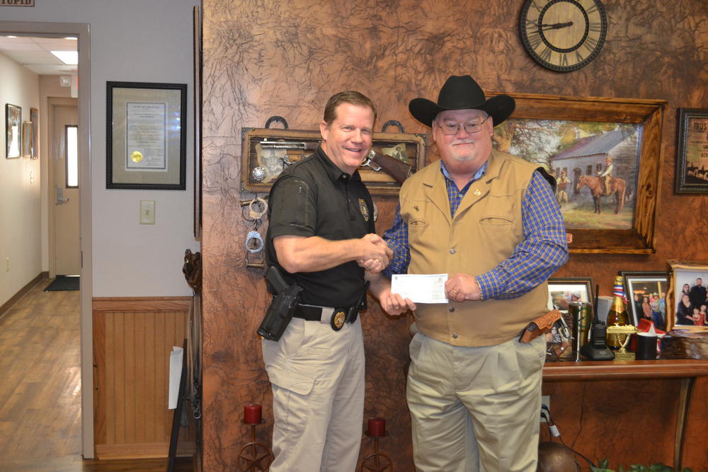 Sheriff Singleton and Darin Archer shaking hands and holding a check