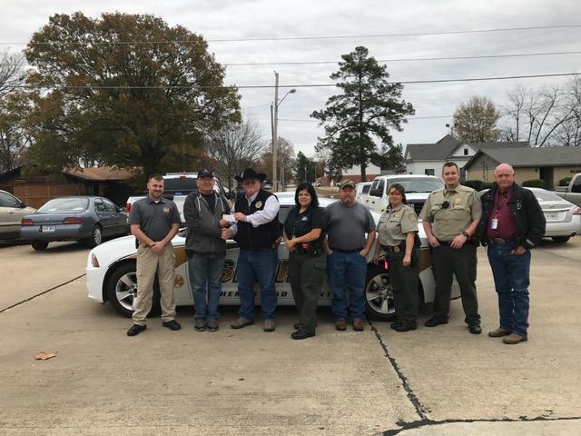 8 members of Plow Boys group standing in front of patrol car