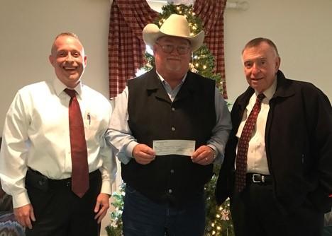 Sheriff Singleton holding a check, standing in between two men in suits