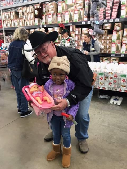 Sheriff Singleton helping young girl pick out a toy doll