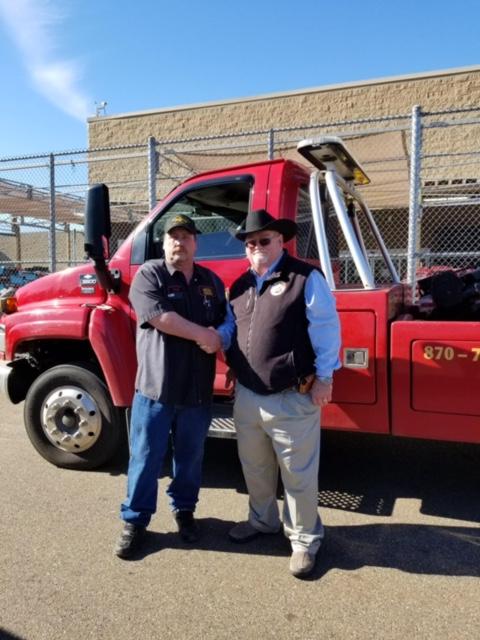 Sheriff Singleton and Gary Reese shaking hands in front of Reese's Wrecker truck