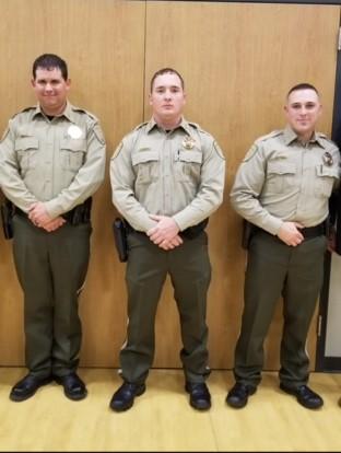 3 deputies standing in uniform in front of a wall