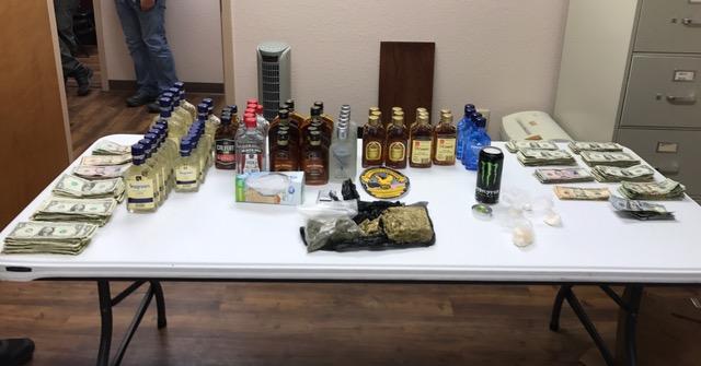money, alcohol, and drugs laid out on a table, results of a raid