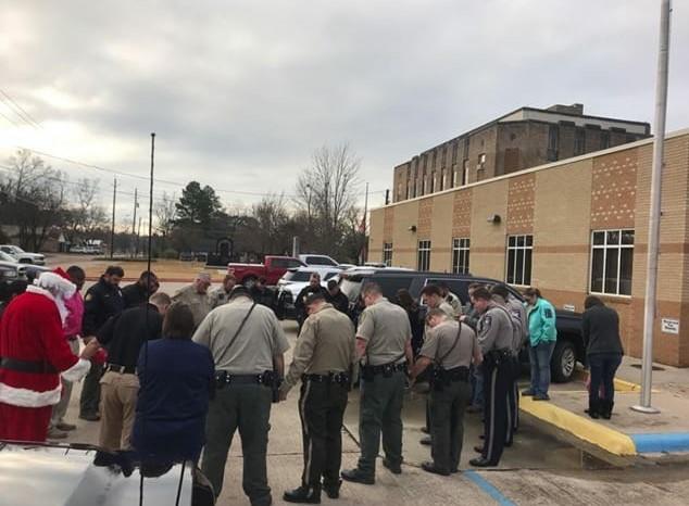 Santa and officers praying in a circle