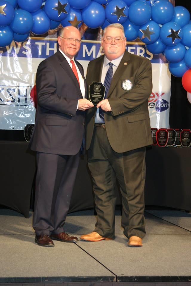 2 men standing holding award