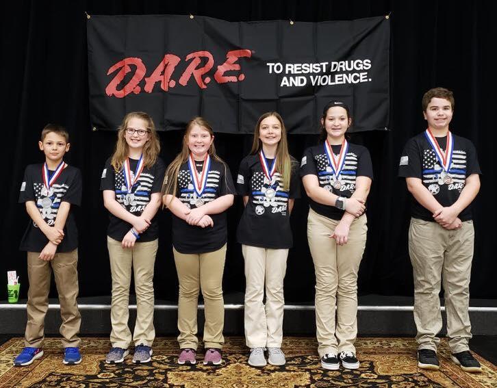 6 DARE students standing in front of black DARE backdrop