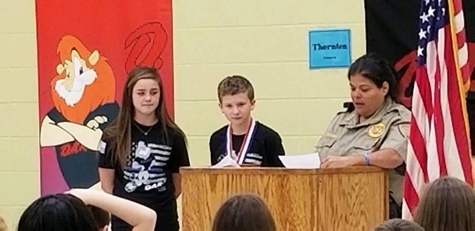Two DARE students standing at podium with officer