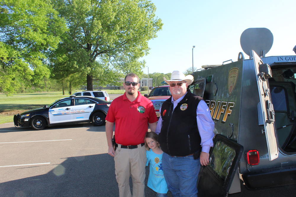 Sheriff's office team with one GMCS student next to sheriff vehicle